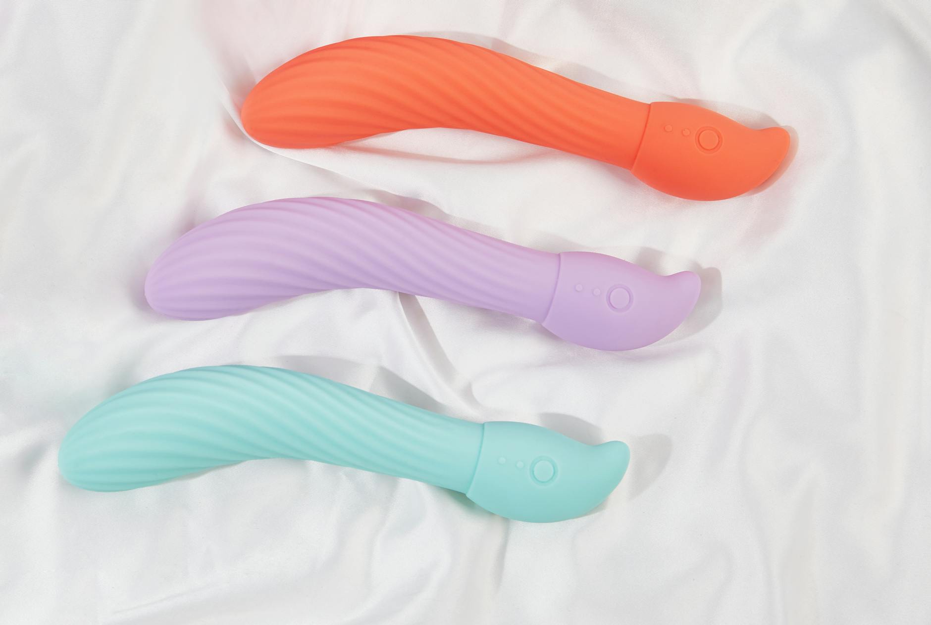 A sleek teal lemon clitoral vibrator resting on smooth white silk fabric