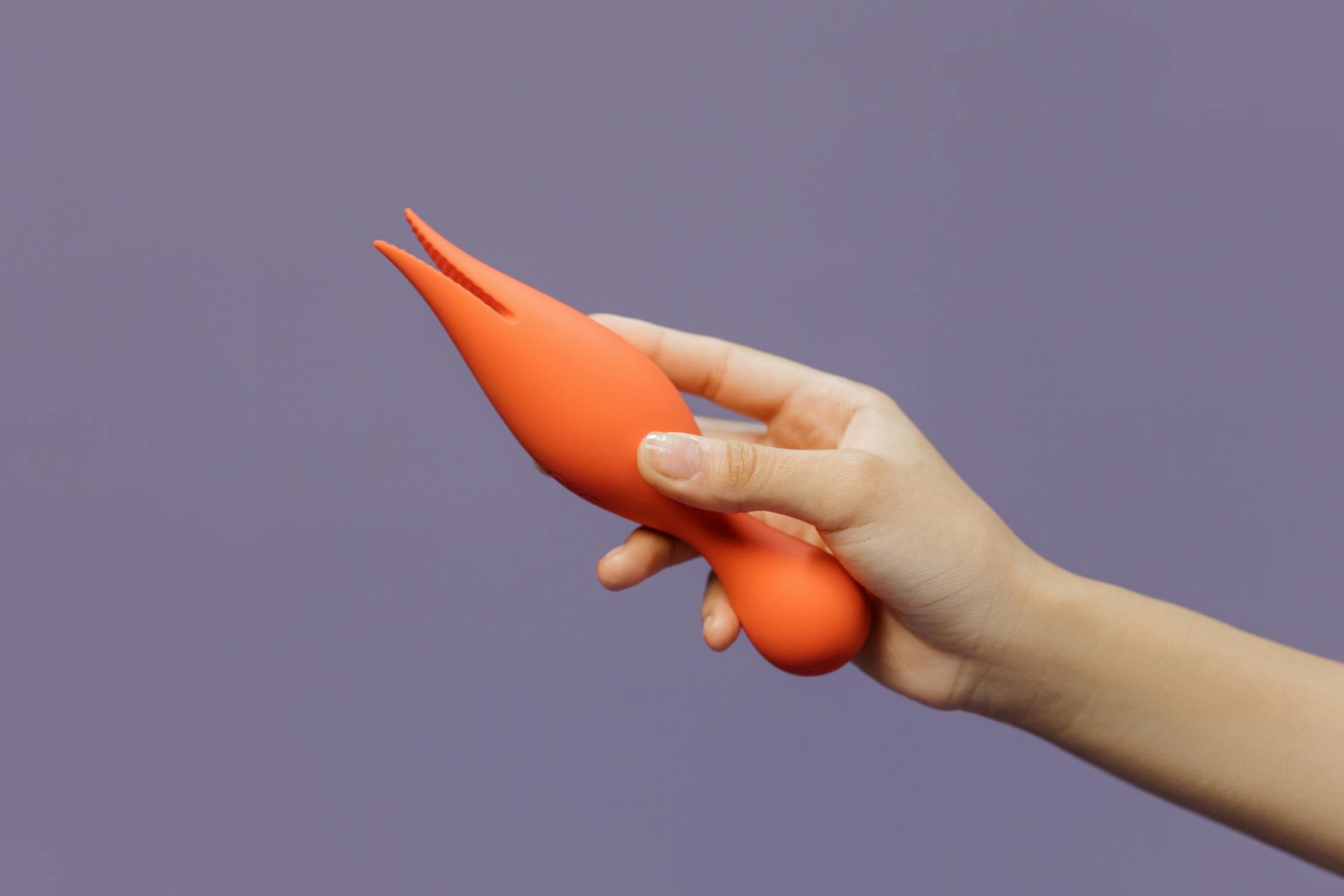 A hand holding a lemon vibrator against a minimalist purple backdrop, symbolizing intimate connection