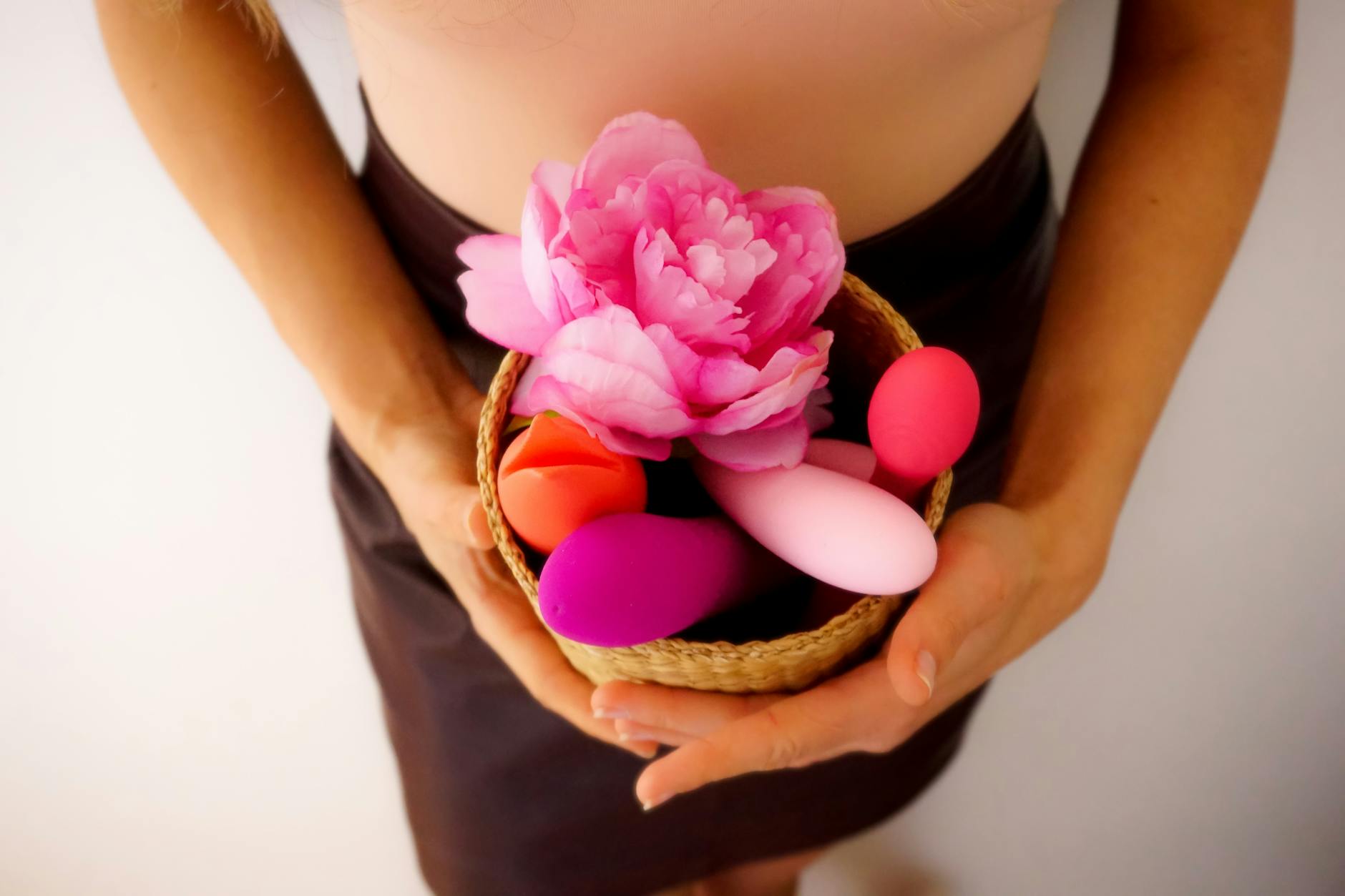 A basket of colorful vibrators and toys arranged with a pink flower, representing couple exploration